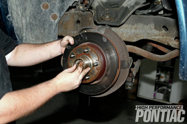 4. The caliper assembly (including disc pads) is carefully stored on the top of the control arm. The rotor is then removed after pulling the dust cap and the cotter pin that holds the spindle nut. The nut is removed with a 11⁄16-inch socket (or wrench) and stored. Note how Mike liberally applied penetrating oil, such as PB Blaster, to the sway bar and control arm to ease disassembly.