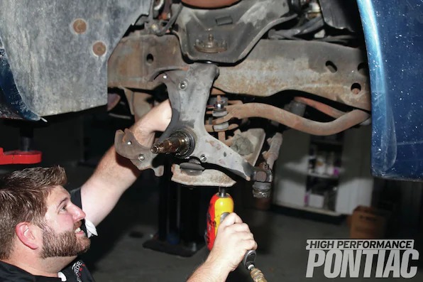 5. The three bolts that attach to the spindle to hold the dust shield in place are removed with a 1⁄2-inch socket. The front sway bar will be removed next by putting a 10mm wrench on the top of the sway-bar end-link bolt and a 10mm socket on the bottom. This style of end link is very popular. Mike struggled removing the nut and bolt due to the accumulated surface rust, but finally prevailed.
